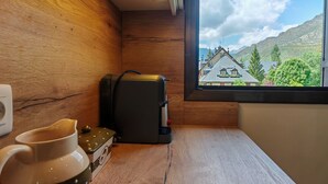 A wooden table with a coffee maker, a mug, and a window with a view of houses and mountains. - Fireplace and modern kitchen. Rustic charm - Aüt 3 (Pla de l'Ermita)