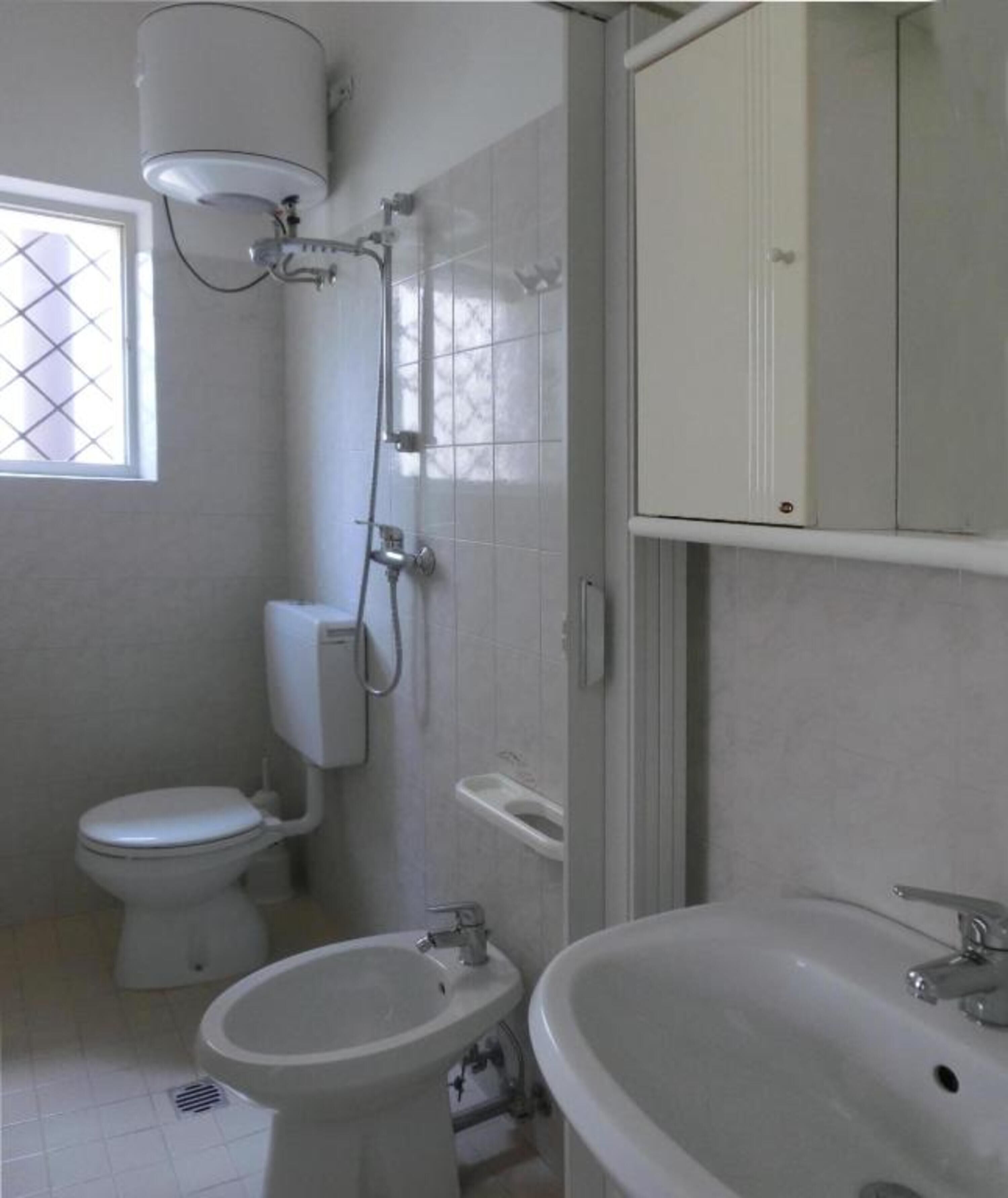 Ein Badezimmer mit Toilette, Bidet, Waschbecken und Dusche mit Wandheizung.