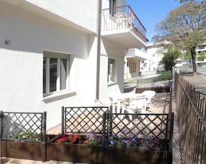 Een wit gebouw met een balkon, terras en bloempotten.