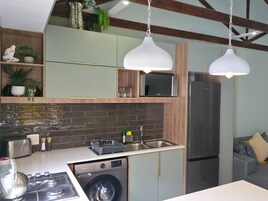 Una cocina compacta equipada con lavadora, microondas y refrigerador.
