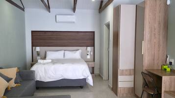 Un dormitorio con cama, mesitas de noche, escritorio, silla y armario.