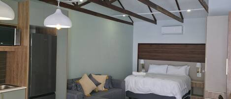 Una habitación de hotel moderna con kitchenette, un sofá, una cama y una mesa de comedor.