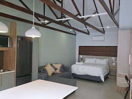Una habitación de hotel moderna con kitchenette, un sofá, una cama y una mesa de comedor.