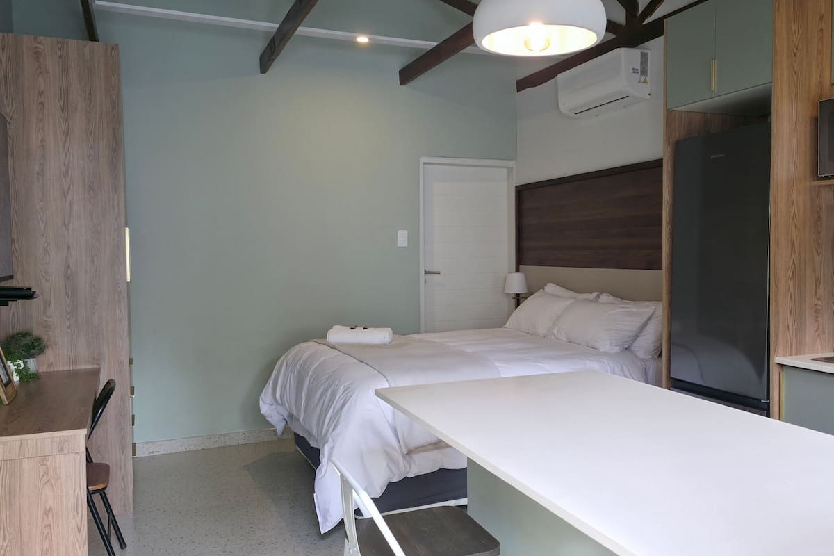 Een slaapkamer met een bed, nachtkastje, stoel en een bureau met een stoel.