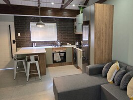 Cocina compacta con una isla central, horno empotrado y lavadora.
