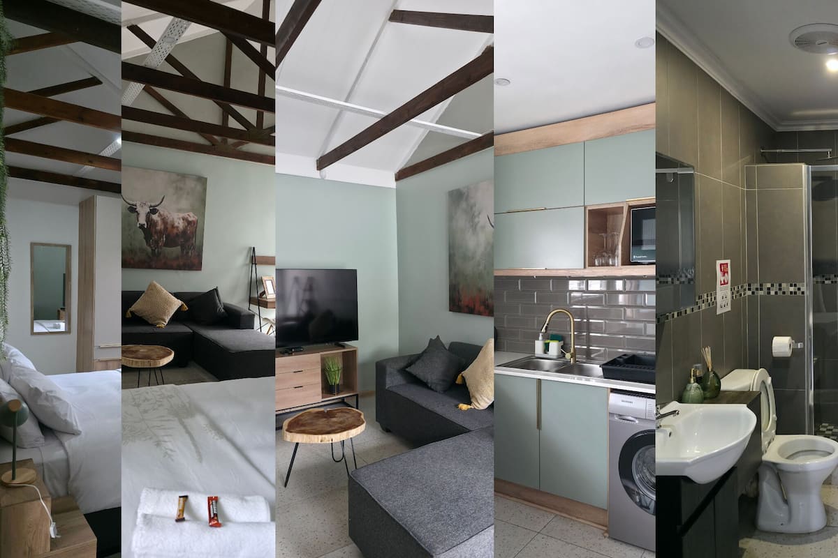 Een moderne hotelkamer met een bed, bank, televisie en een klein zithoekje.