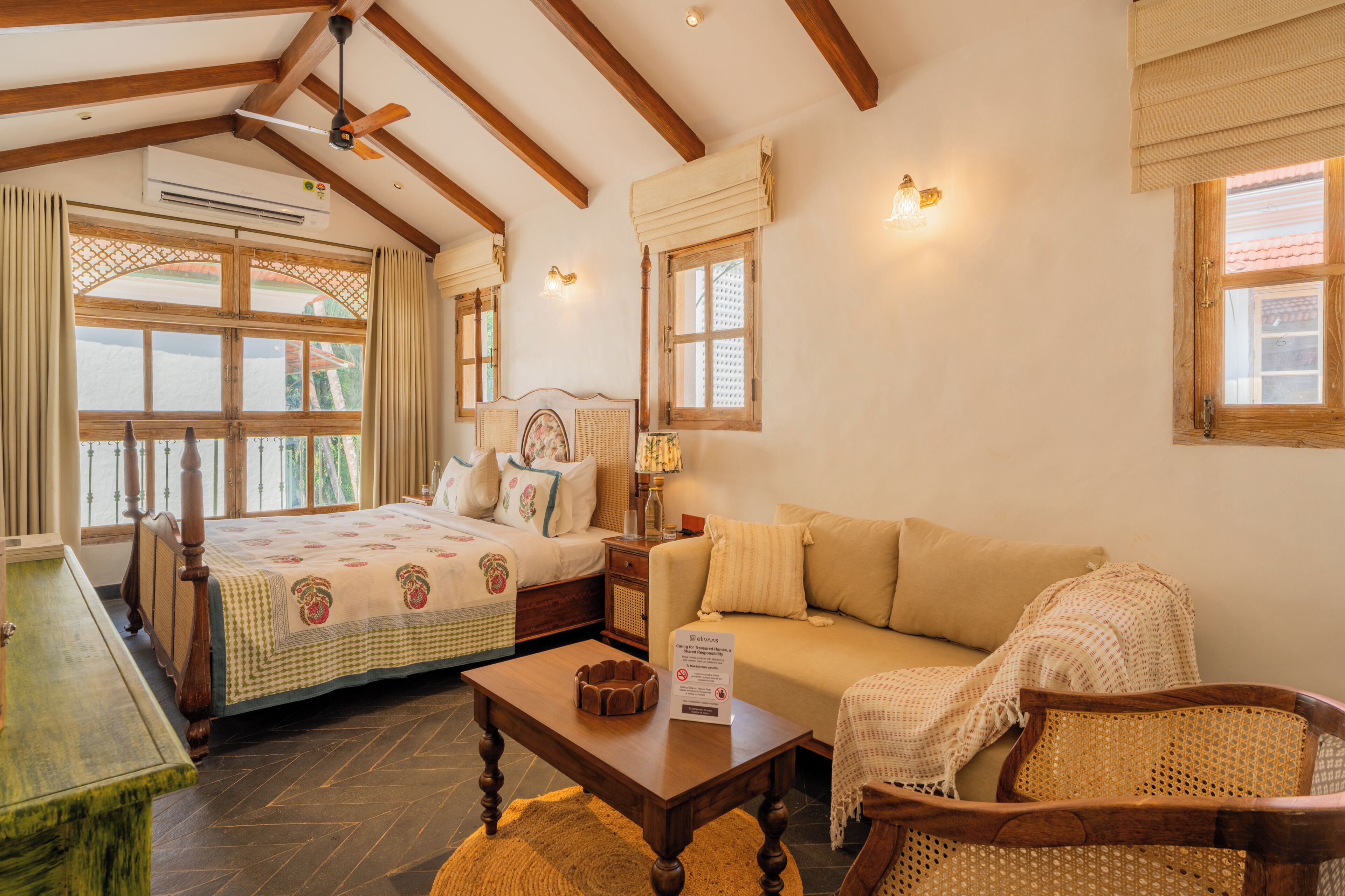 Una habitación con cama, sofá, una mesa de madera y una ventana con cortinas.
