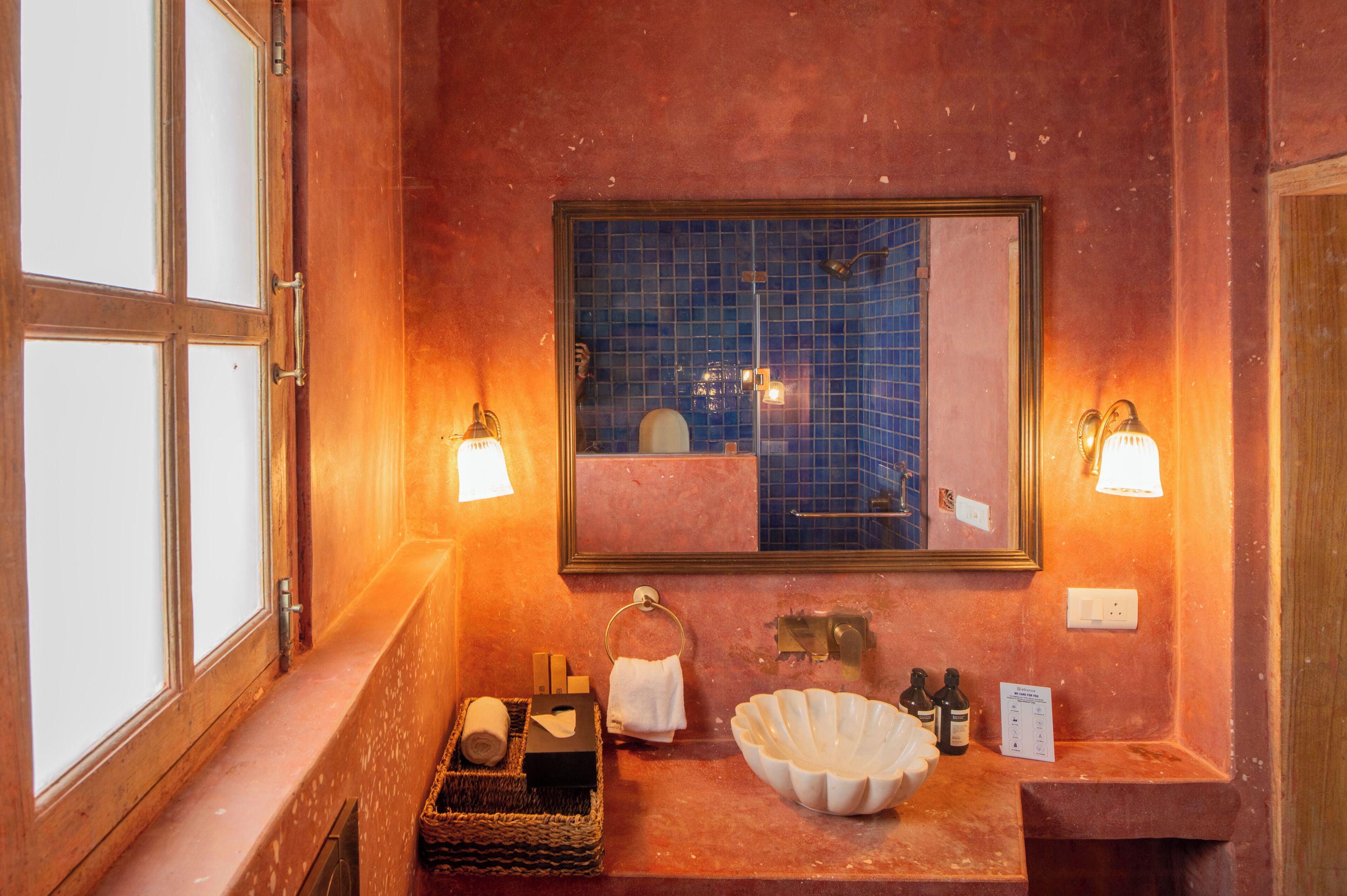 Un baño con un espejo grande, dos luces empotradas en la pared, un lavabo con un cuenco decorativo y una ventana con vidrio esmerilado.