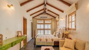 A room with a bed, a sofa, a wooden table, a desk, and a window with curtains.