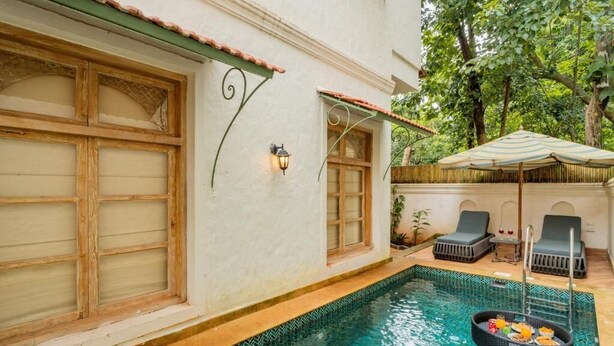 A poolside area with a wooden door, a small window, and two lounge chairs.