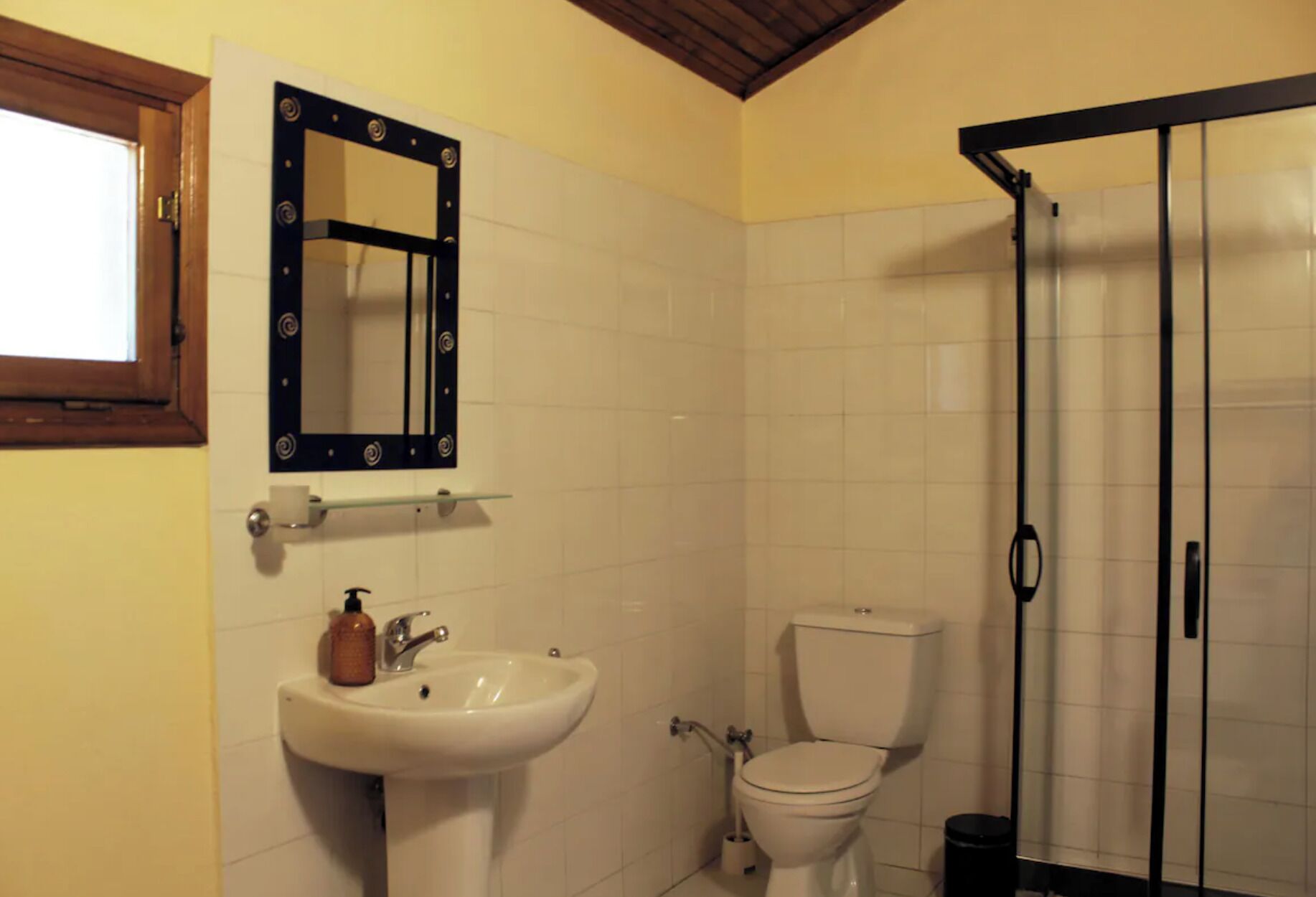 Casa de banho com lavatório, sanita e cabine de duche.