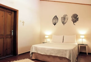 Un dormitorio con cama, dos lámparas de noche, un armario de madera y decoración en la pared.
