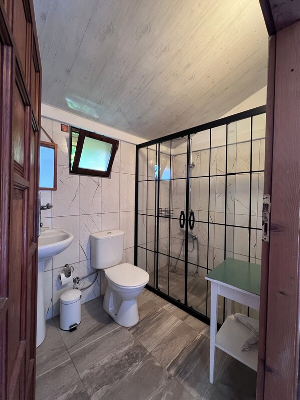 A bathroom with a toilet, sink, and shower enclosure. - Argos Çıralı (Kemer)