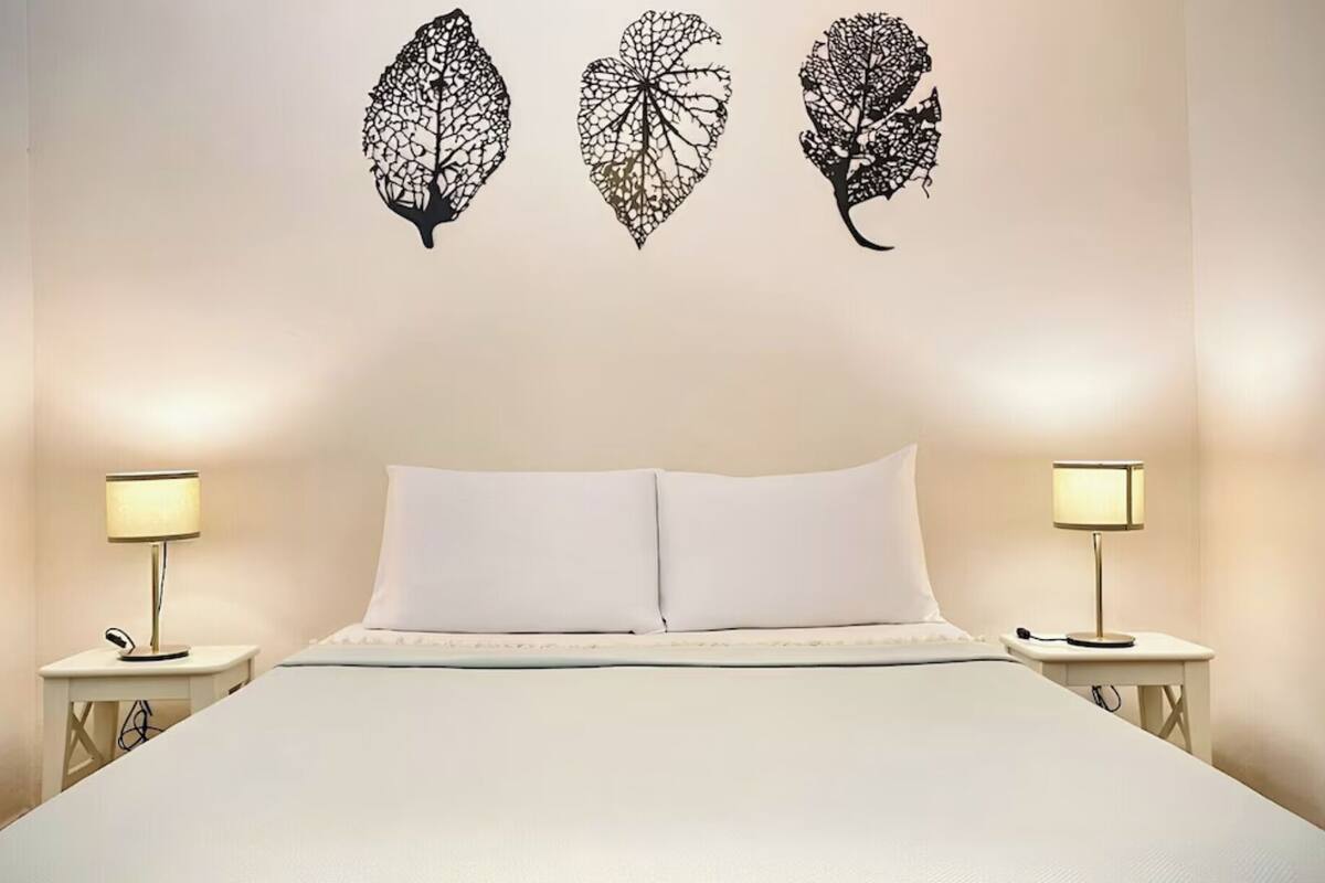 Une chambre à coucher comprenant un lit, deux tables de chevet et trois œuvres d’art accrochées au mur.