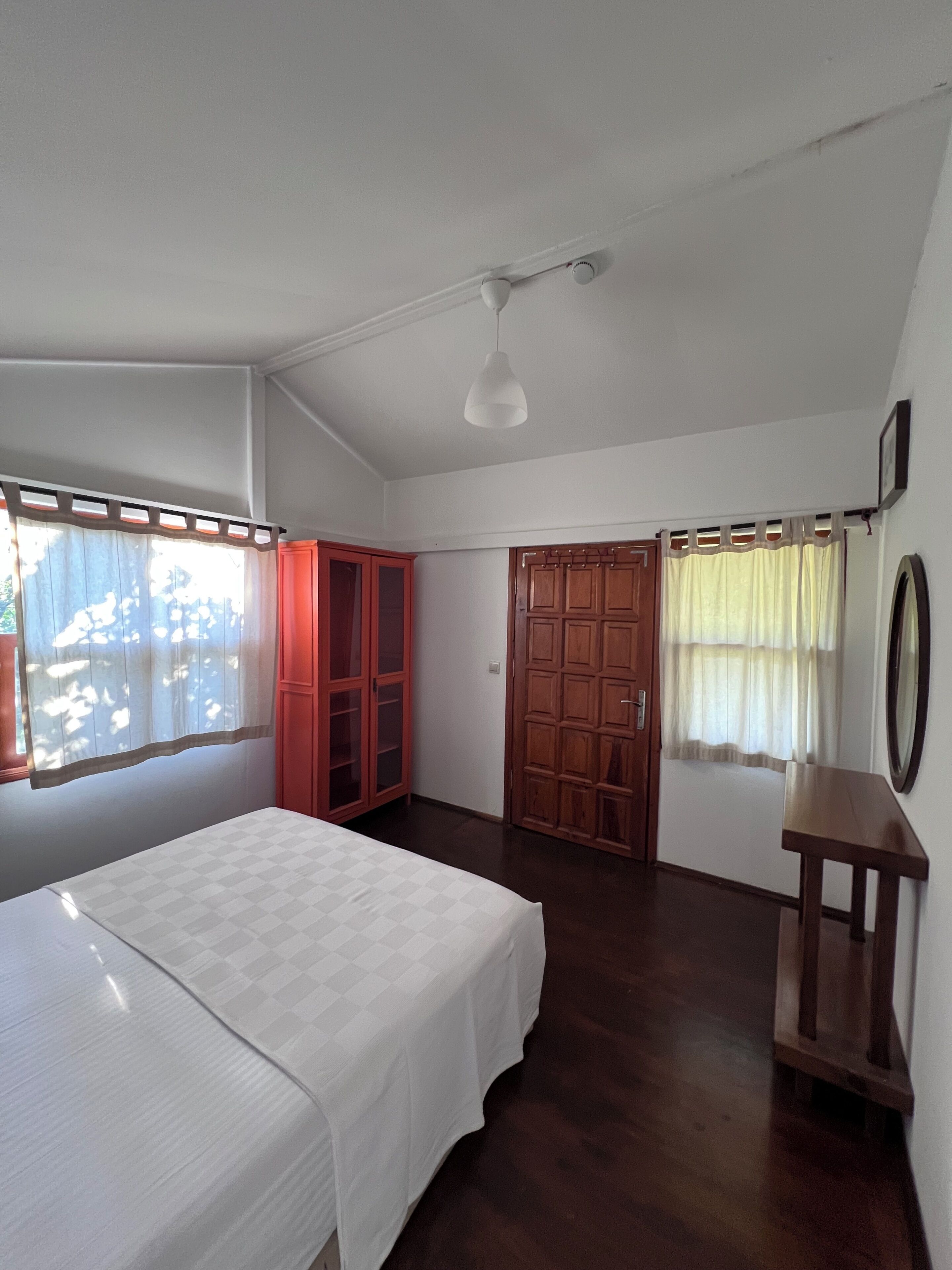 A bedroom with a bed, a wardrobe, a door, a mirror, and a ceiling light.