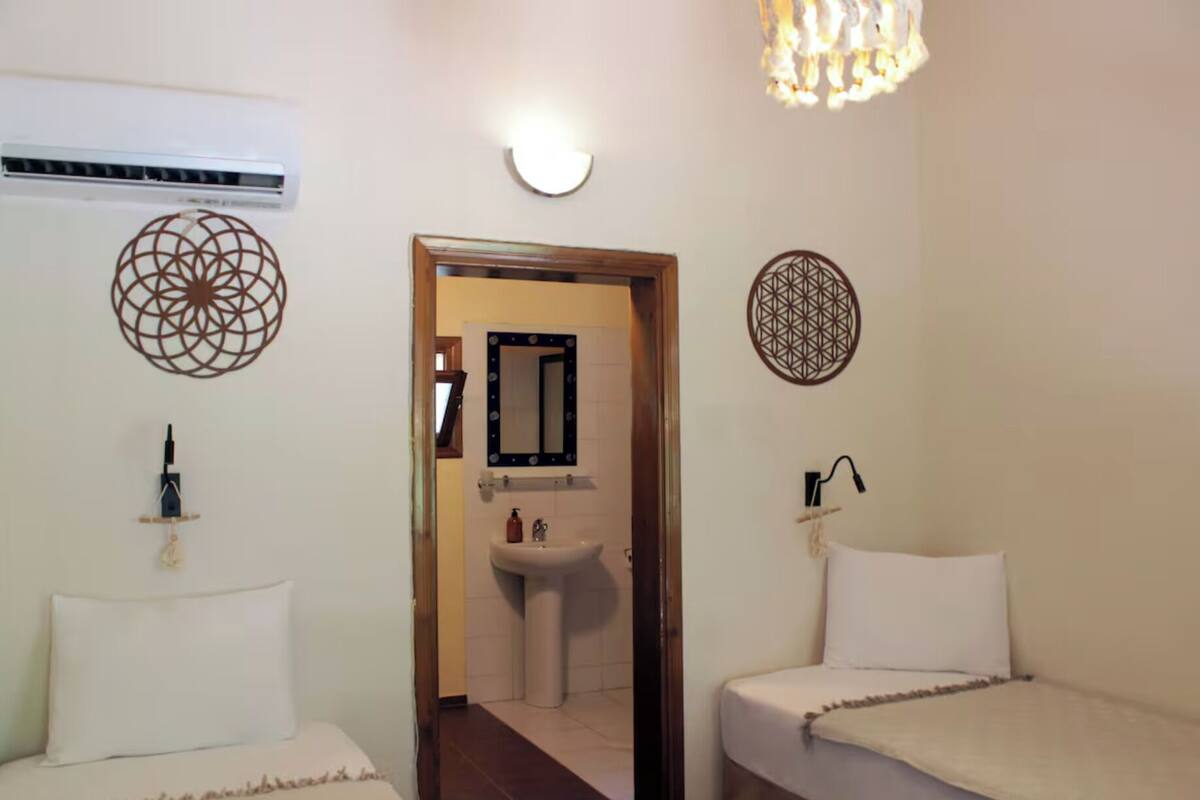 Une chambre d’hôtel comprenant un lit, une table de chevet, un miroir, un lavabo et des œuvres d’art décoratives sur les murs.