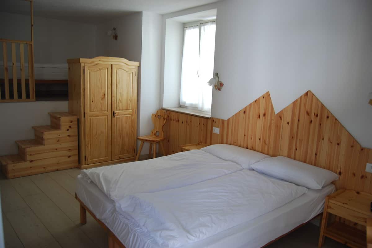 Une chambre à coucher avec un lit en bois, une armoire, une fenêtre et un escalier en bois.