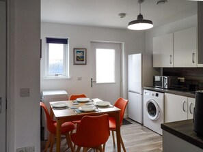 Une cuisine compacte comprenant un coin repas, un lave-linge et un four à micro-ondes.