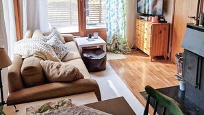 A living room with a sofa, a coffee table, a television, and a fireplace. - 4 Star Holiday Home in Mariefred (Mariefred)