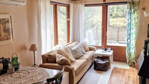A cozy room with a sofa, a table, and a window with curtains. - 4 Star Holiday Home in Mariefred (Mariefred)