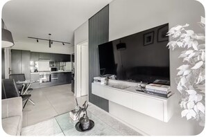 Ein modernes Wohnzimmer mit einer Couch, einem Couchtisch und einem an der Wand befestigten Fernseher.