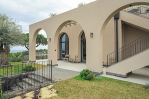 A building with arched windows, a staircase, and outdoor seating. - Flora Sicula - Cultivating Hospitality (Giarre)