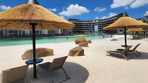 A resort with a swimming pool, lounge chairs, and thatched umbrellas. - Crystal Ace Lagoon & Pool Bliss (Johannesburg)
