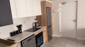 A modern kitchen with white cabinets, a built-in oven, a dishwasher, and a refrigerator. - Crystal Ace Lagoon & Pool Bliss (Johannesburg)