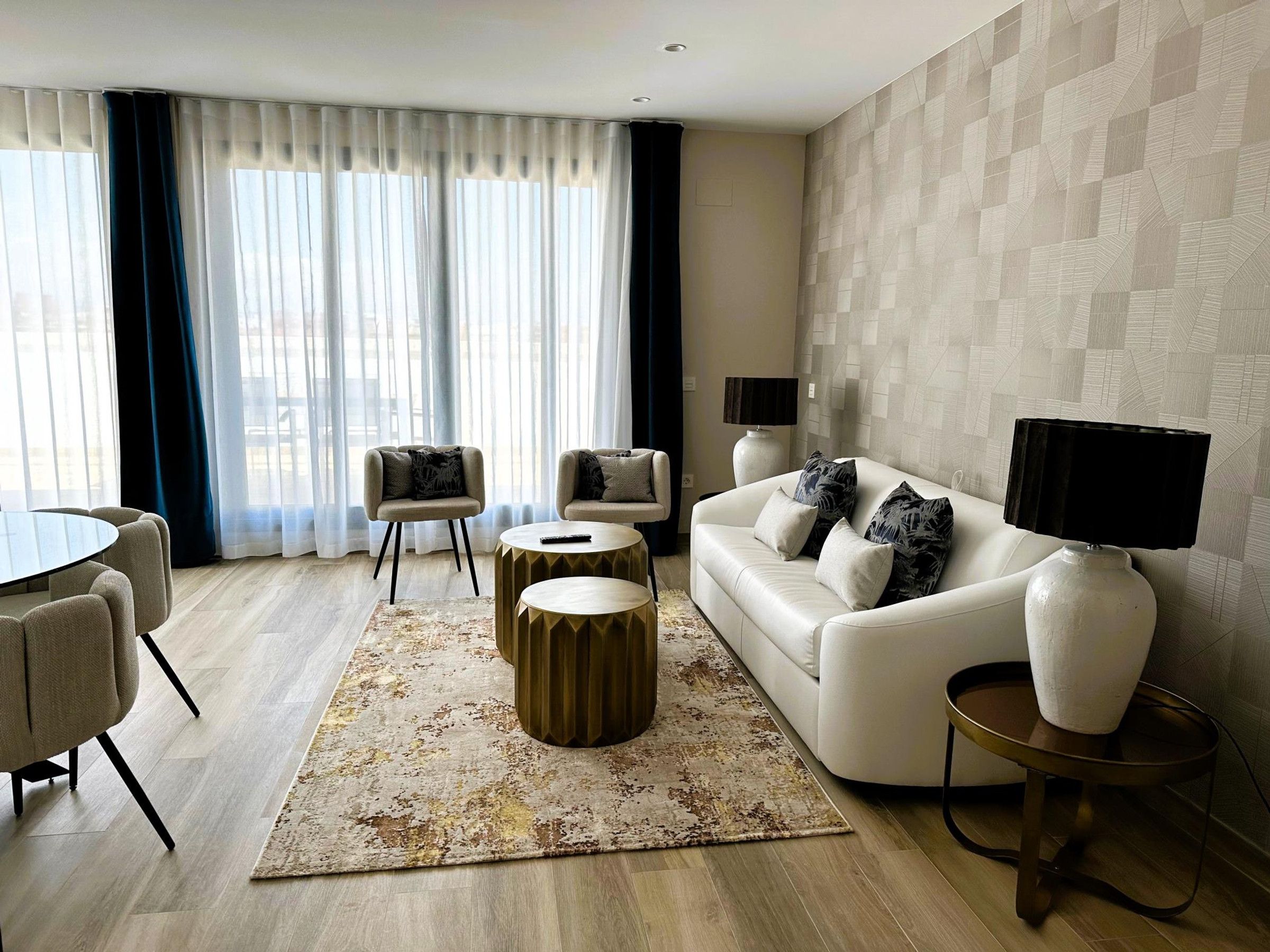 Ein modernes Wohnzimmer mit einer Couch, Sesseln, einem Couchtisch und einem Fernseher.