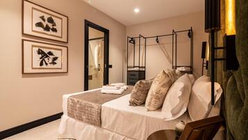 Un dormitorio con cama, mesita de noche, espejo y dos cuadros en la pared.