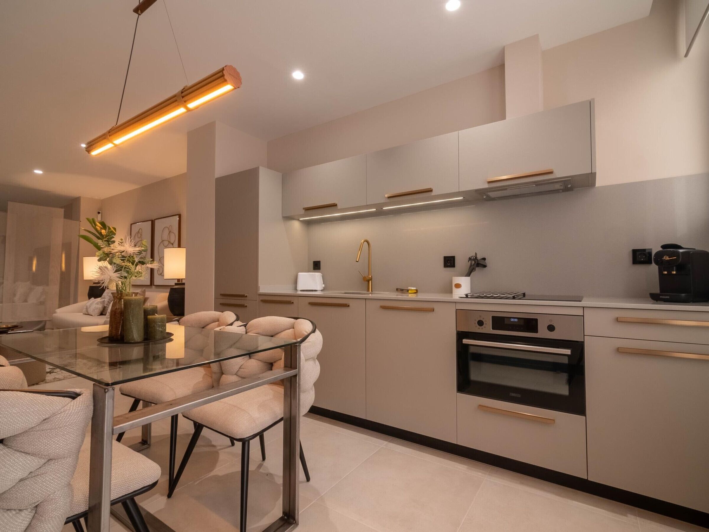 Una cocina moderna con una mesa de comedor de vidrio, electrodomésticos de acero inoxidable y un diseño minimalista.