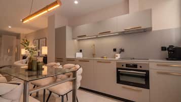 Una cocina moderna con una mesa de comedor de vidrio, electrodomésticos de acero inoxidable y un diseño minimalista.