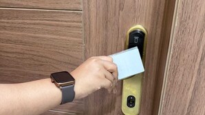 A hand inserting a card into a door lock. - Infinity Hotel (Kanpur)
