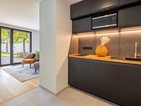 A modern kitchen with dark cabinetry, a built-in microwave, and a wooden countertop. - Spacious room with terrace and pool (SUCE-SUR-ERDRE)