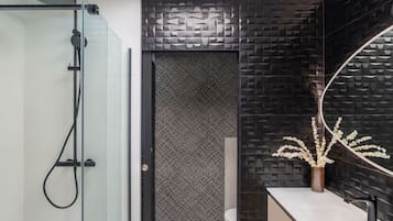 A modern bathroom with a glass shower enclosure, a patterned wall, and a vanity with a mirror.