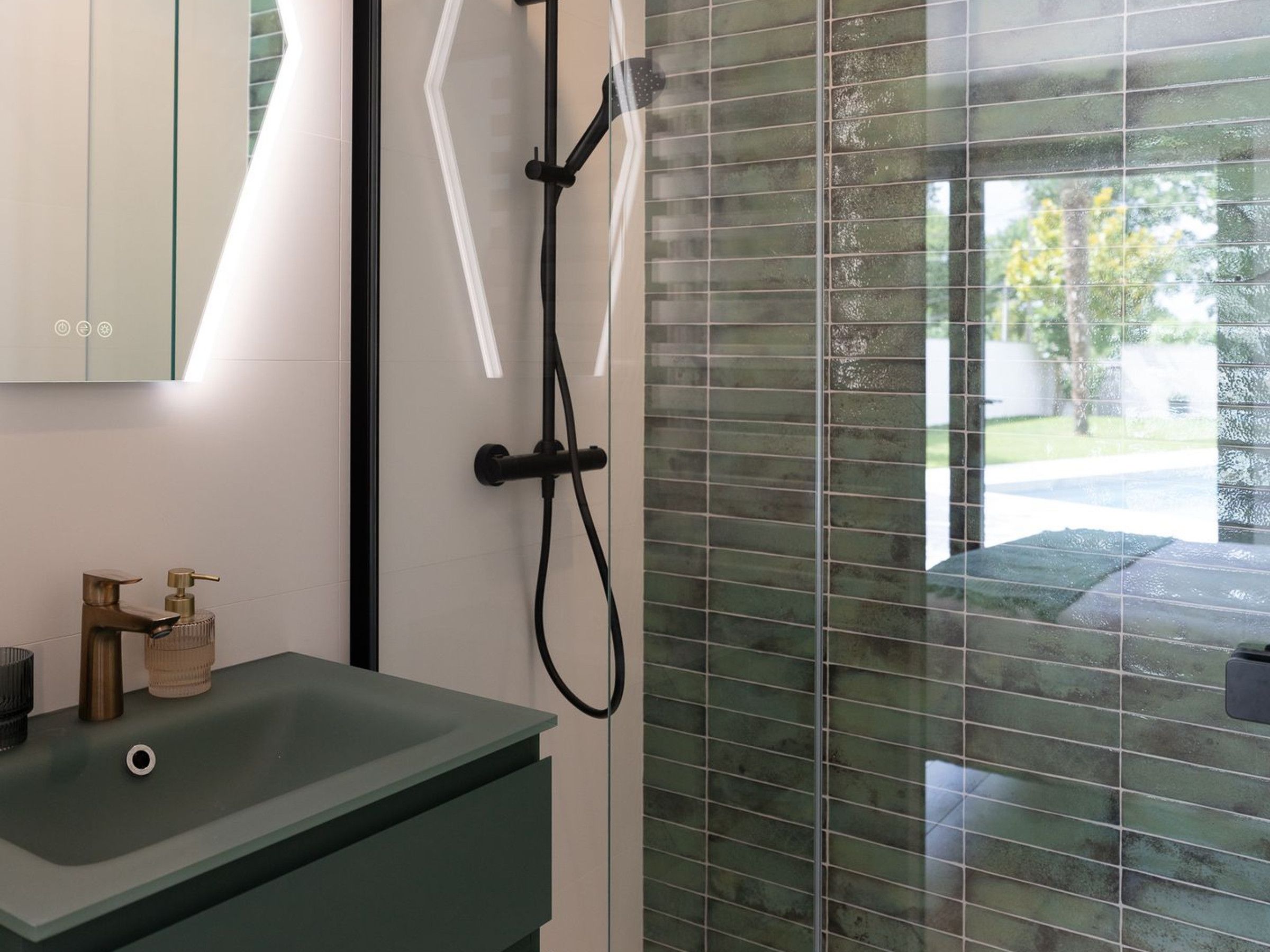 A modern bathroom with a glass shower enclosure, a green sink, and a mirror.