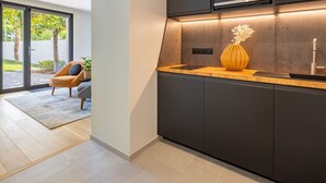 A modern kitchen with dark cabinetry, a built-in microwave, and a wooden countertop. - Ground floor room with terrace (SUCE-SUR-ERDRE)