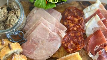 Una tabla de embutidos con diversos tipos de carne, pan y ensalada.