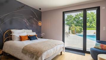 Une chambre avec un lit, une table de chevet, une lampe, une fenêtre et une vue sur une piscine extérieure.