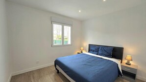 Une chambre à coucher avec un lit, deux lampes de chevet, une fenêtre et une table de chevet.