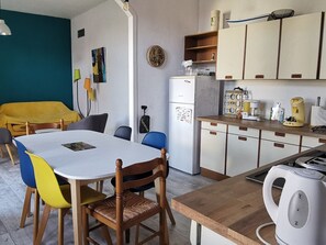 A compact kitchen with a dining table, chairs, a refrigerator, and a kettle. - House near water pond - 6 guests (L'Aiguillon-sur-Mer)