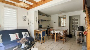 Un espacio habitable compacto con sofá, mesa de comedor, zona de cocina y un espejo.