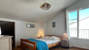 Un dormitorio con cama, lámparas de noche, una ventana con cortinas y un ventilador de techo.