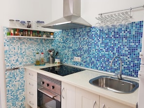 A kitchen with a tiled backsplash, a stainless steel sink, and a range hood. - Modern and comfortable apartment - València (Valencia)