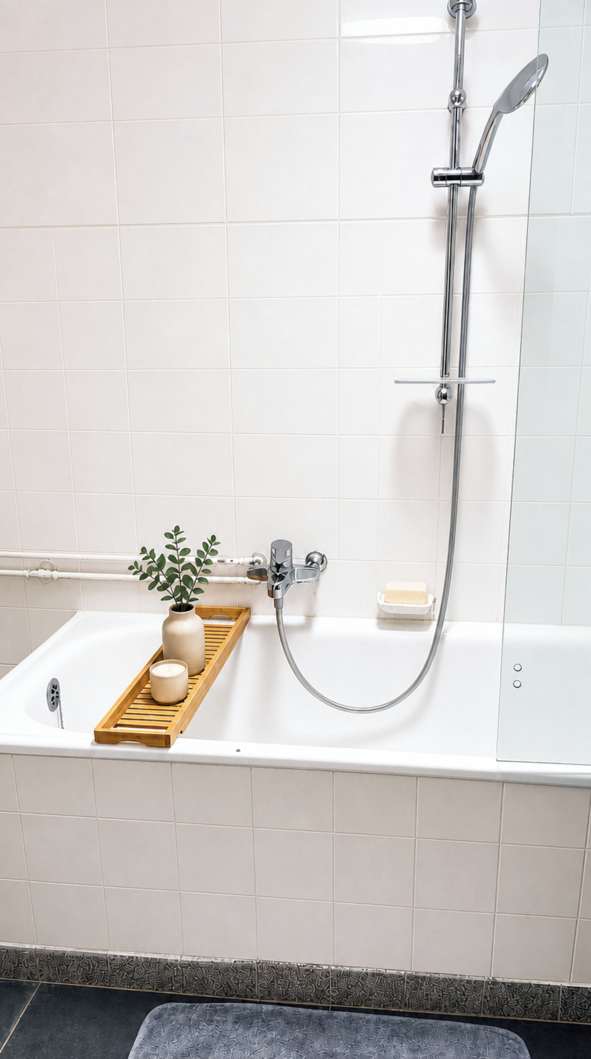 Ein Badezimmer mit Badewanne, Dusche und einem Holztablett mit Pflanze und Kerze.