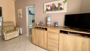 A living room with a beige sofa, wooden entertainment unit, TV, and artwork. - House near sea, sunny terrace - 6 guests (Saint-Hilaire-de-Riez)