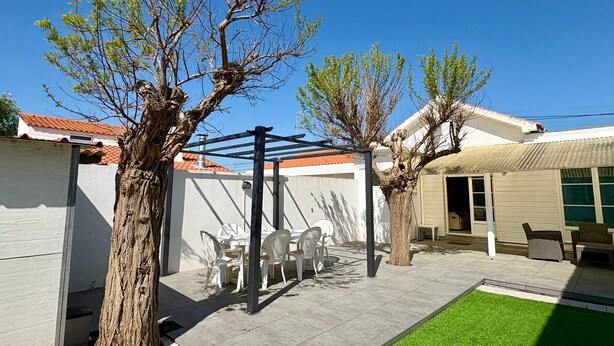 A patio area with a pergola, outdoor seating, and a small lawn. - House near sea, sunny terrace - 6 guests (Saint-Hilaire-de-Riez)