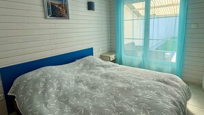 A bedroom with a bed, a picture on the wall, a window with curtains, and a small table. - House near sea, sunny terrace - 6 guests (Saint-Hilaire-de-Riez)