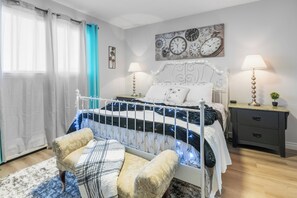 A bedroom with a bed, bedside tables, a nightstand, a wall clock, and a window with curtains. - Oasis away (Edmonton)