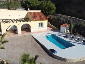 Un'area piscina con vasca, lettini e un piccolo edificio con tetto in tegole.